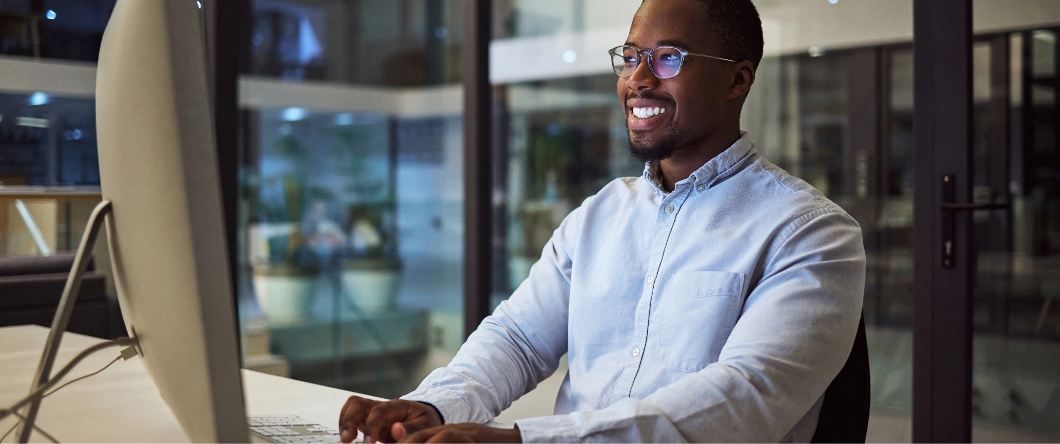 Pessoa sorrindo enquanto utiliza um notebook com expressão positiva e produtiva.